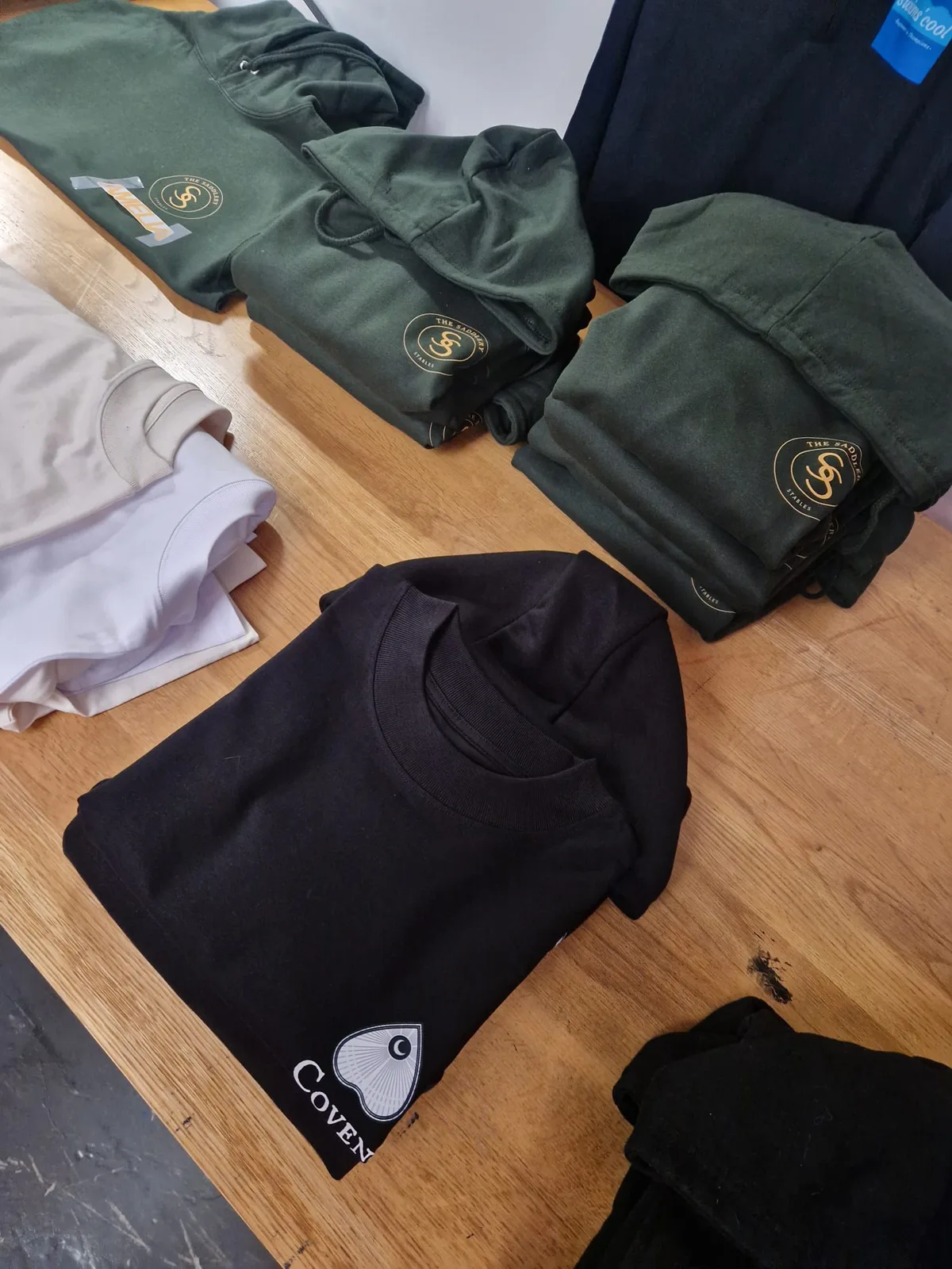 Assorted branded t-shirts and folded clothing on the worktable